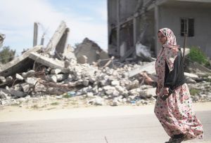 woman walking along the rubbles in Gaza