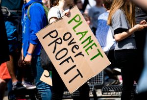 Banner with text "Planet over Profit" held by a person during a demonstration
