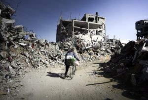 a person on a bike passing through Jabalia's ruins in Gaza