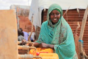 Aqiqah, a mother of three collects water from an Oxfam-constructed water tank in Beledweyne, significantly reducing the burden on women and girls who previously had to walk long distances to access water.