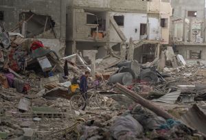A boy pushes his bike through the rubble of destroyed buildings in Gaza