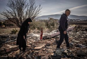 Ruba and Hassan Chamas walk through the ruins of their bombed home; she mourns her son lost in the strike."