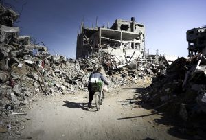 Man cycles his bike in the Gaza ruins.
