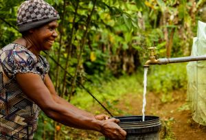 Lavin of Nogorunte community in Papua New Guinea (PNG), shows off the new tap outside her home built by Oxfam's Kōtui Programme