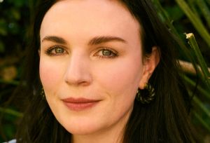 Irish comedian Aisling Bea sits for a portrait and holds her gold necklace holding her baby Saoirse.