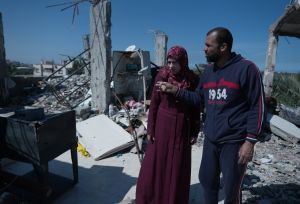 Woman and man walk around destroyed WASH facilities in Gaza.