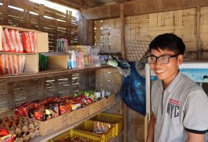 Chansouk standing in front of his shop's shelves