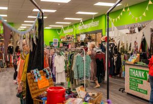shop floor with clothes hanging on rails and a green banner.
