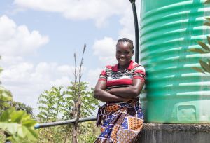 Angela Chiyala, 38, Vice Chairperson of a Farmer Field School in Namwala, Southern Province, Zambia stands near the solar-powered water tank that supplies water to the farmer field school garden.