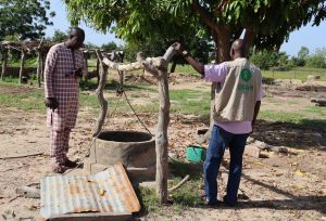 Resident and Oxfam staff in front of a water well