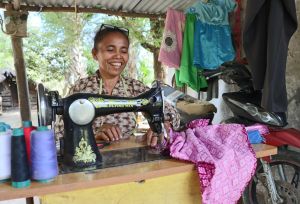 Agnes (age 46) sews a dress at her work space
