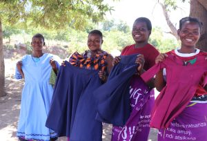 Four women from the The Chisomo Tailoring Club holding skirts and dresses they have made as part of the club.