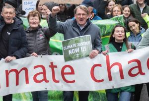 A group of people hold up their hands and hold a banner saying climate chaos