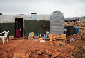 woman stands in her provisional shelter