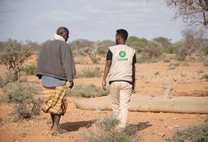 Oxfam staff member and Somalian community member walk through dry land.