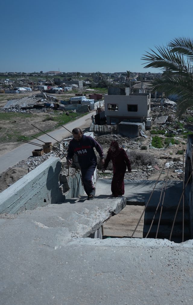 Suhad and her husband walking in the rubbles of their old house.