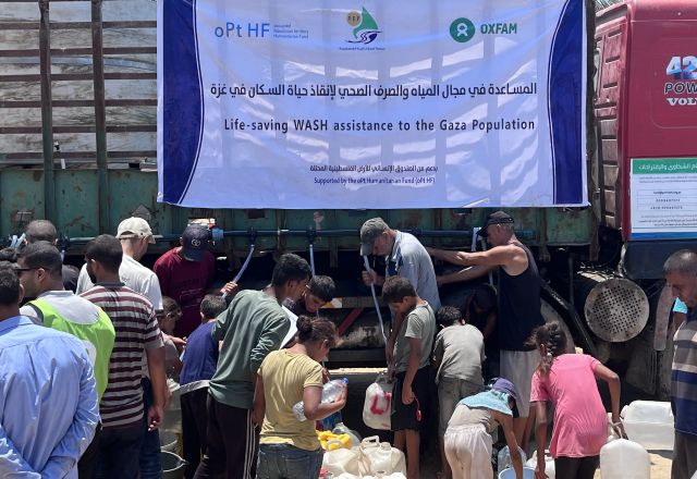 Group of displaced people trying to fill their jerrycans and buckets with water.