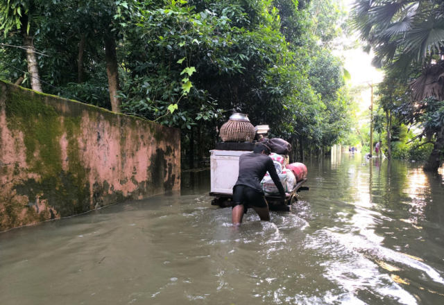 Man in Bangladesh pushing a cart in a flooded street - water up to his knees.