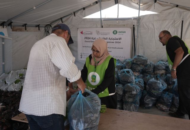 A man is receiving a vegetable basket distributed by Oxfam and partners in Deir Al Balah in the middle of Gaza.