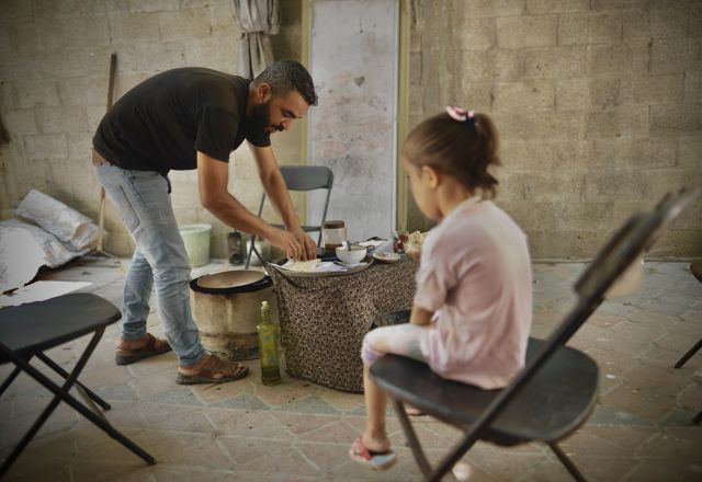 A dad preparing food from an Oxfam food parcel for his kid in Gaza. Up to 21,000 people are dying each day from conflict-fuelled hunger around the world