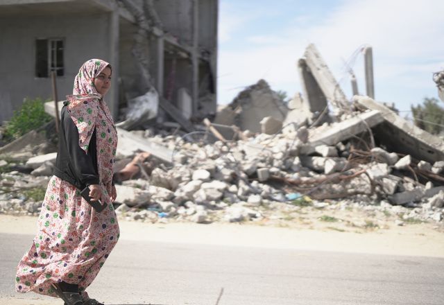 A woman walking in the street of Gaza surrounded by rubbles