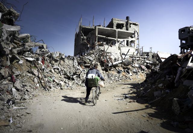 a person on a bike passing through Jabalia's ruins in Gaza