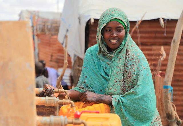 Aqiqah, a mother of three collects water from an Oxfam-constructed water tank in Beledweyne, significantly reducing the burden on women and girls who previously had to walk long distances to access water.