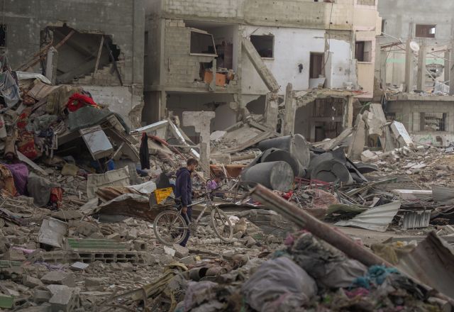 A boy pushes his bike through the rubble of destroyed buildings in Gaza