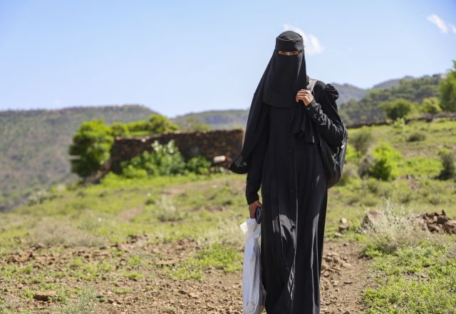 Nahla Abdo walks along a rural path in Al-Ma’afer, Yemen, carrying bags