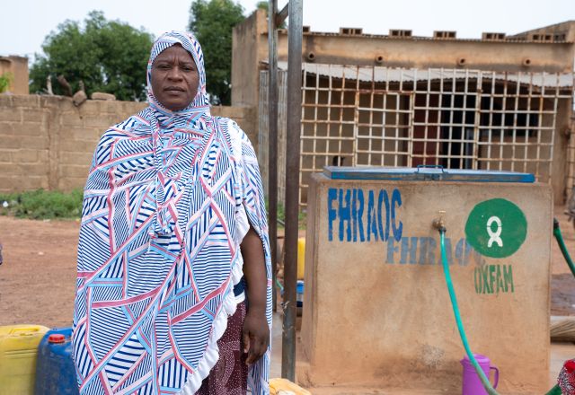 Adjaratou Sawadogo stands beside a water facility built by Oxfam in Boulsa, Burkina Faso.