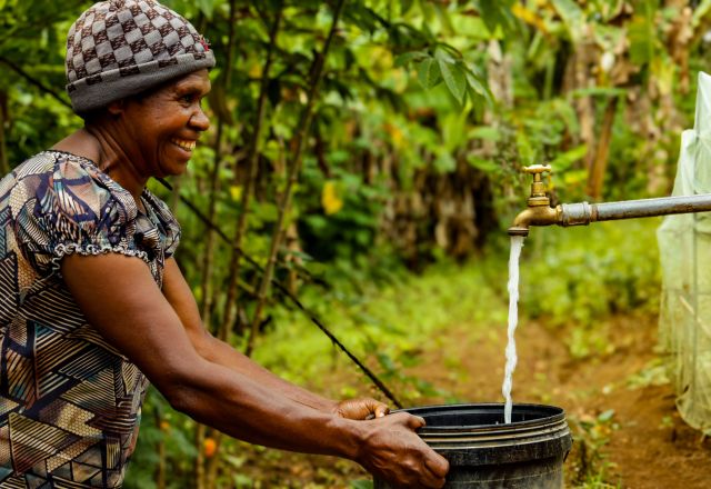 Lavin of Nogorunte community in Papua New Guinea (PNG), shows off the new tap outside her home built by Oxfam's Kōtui programme