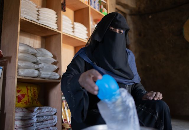 Oqba weighs out kilos of rice at her scales. She ensures each bag is properly weighed and arranged for sale