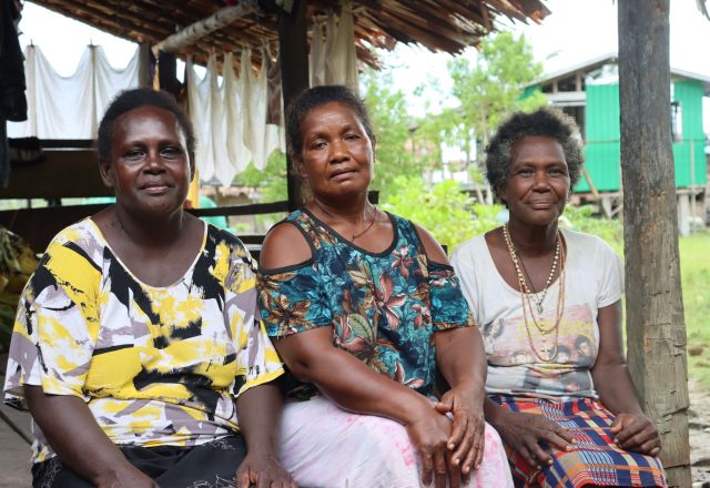 Three women from rural Malaita, Solomon Islands, smile together as participants in Oxfam’s Kōtui programme supporting women’s empowerment through savings clubs.