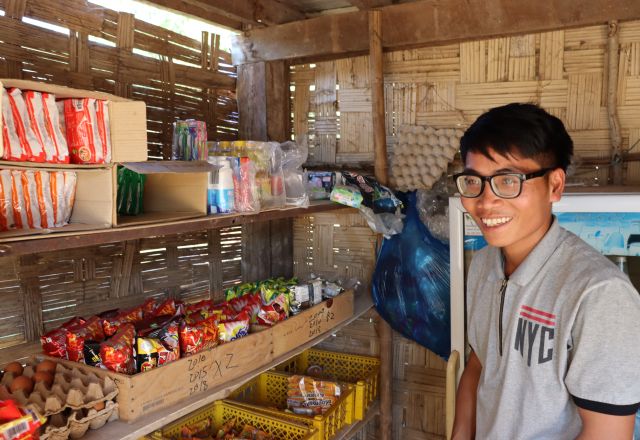 Chansouk standing in front of his shop's shelves