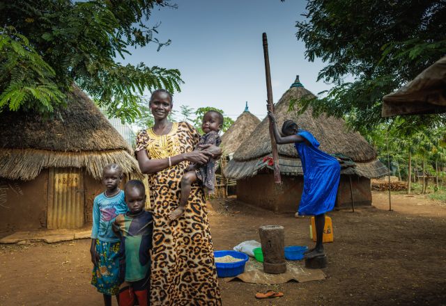Ngakutoth Biel standing in front of their village with her children