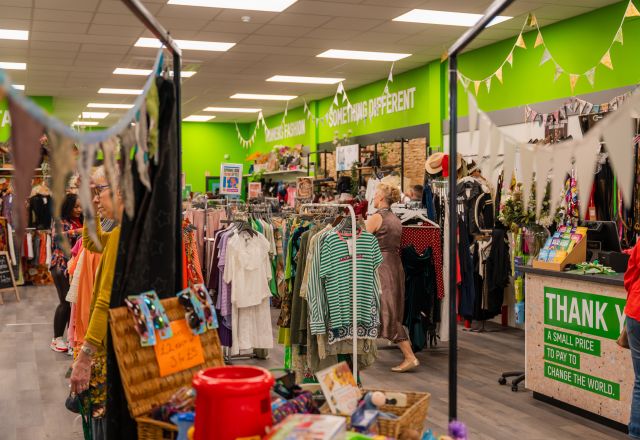 shop floor with clothes hanging on rails and a green banner.