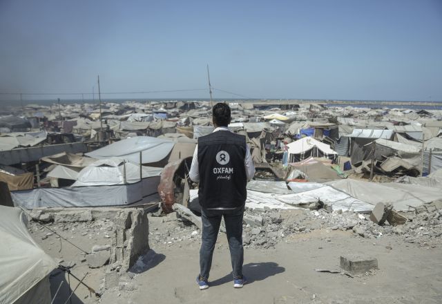 Osama, Oxfam Staff, walks among tents and rubble in Gaza City