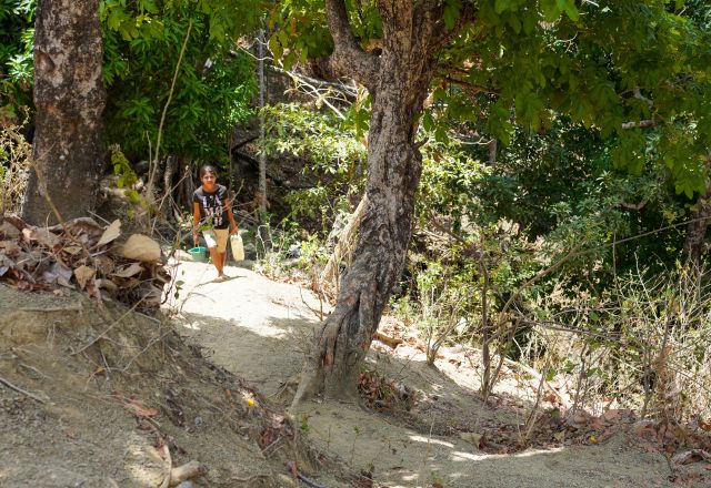 Domingas collects water for her community's vegetable garden.