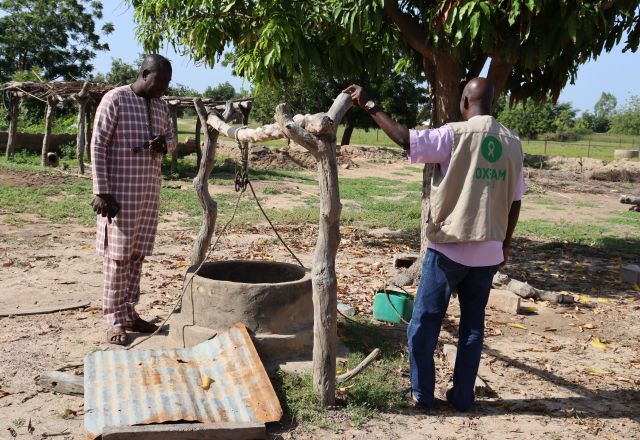 Mali resident and Oxfam staff in front a water well