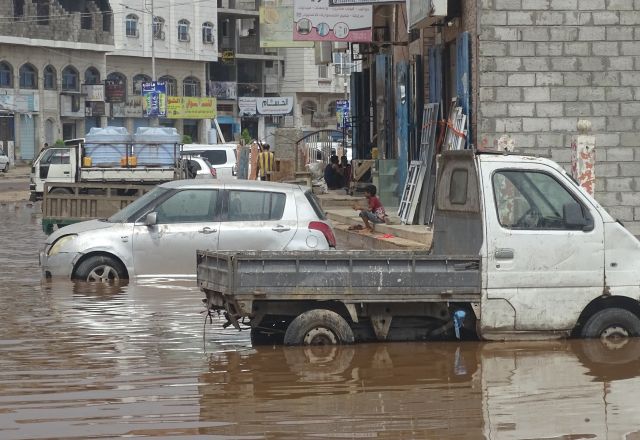 Two cars stopped in a street filled with water.