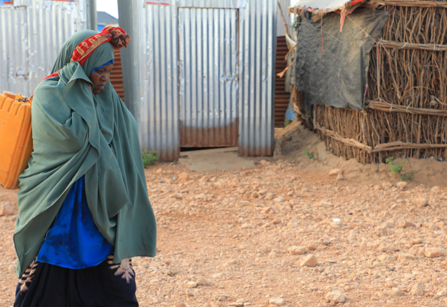Woman walking along a path carrying jerrycan with water