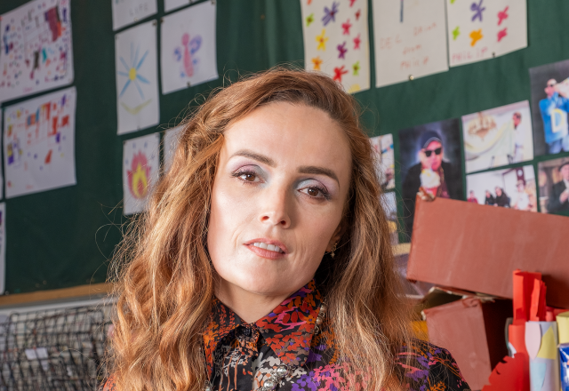 Emma Doran wearing a purple, orange, black and pink blouse looking into camera.
