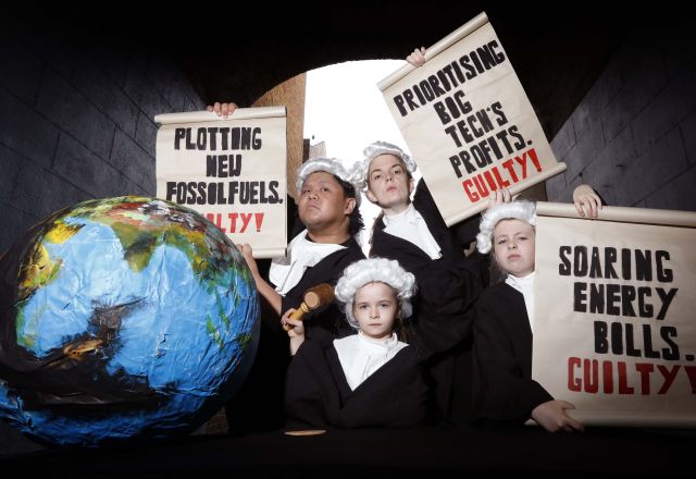 Four young people holding scrolls dressed as judges.