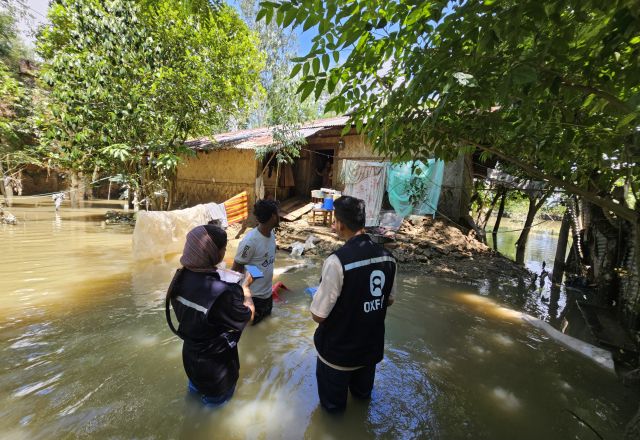 Three people standing in flood water in Bangladesh.