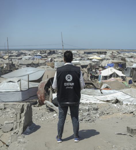 Osama, Oxfam Staff, walks among tents and rubble in Gaza City