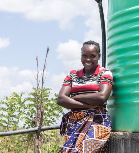 Angela Chiyala, 38, Vice Chairperson of a Farmer Field School in Namwala, Southern Province, Zambia stands near the solar-powered water tank that supplies water to the farmer field school garden.