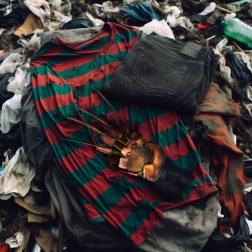 Image of Freddy Krueger Halloween outfit on top of a pile of clothes in the landfill.AI generated content.
