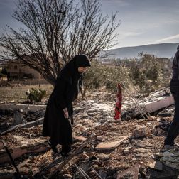 Ruba and Hassan Chamas walk through the ruins of their bombed home; she mourns her son lost in the strike."