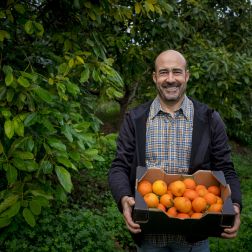 Paco Alabau, standing with a box of oranges in the middle of the field