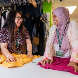 Two volunteers at an Oxfam Ireland Shop, sorting donated clothes.